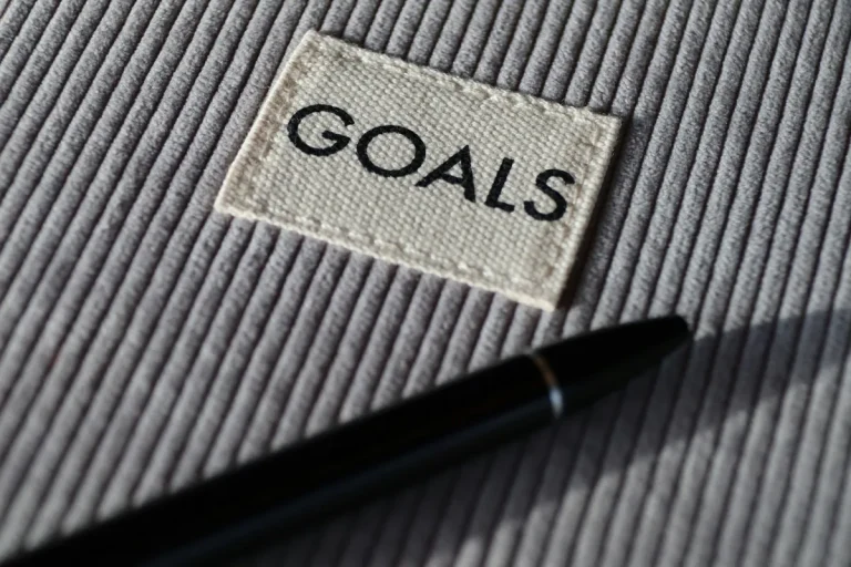 black pen on grey textile with a tag that says "GOALS"