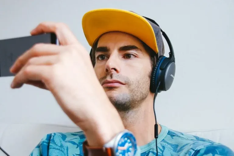A man wearing headphones and watching a phone.