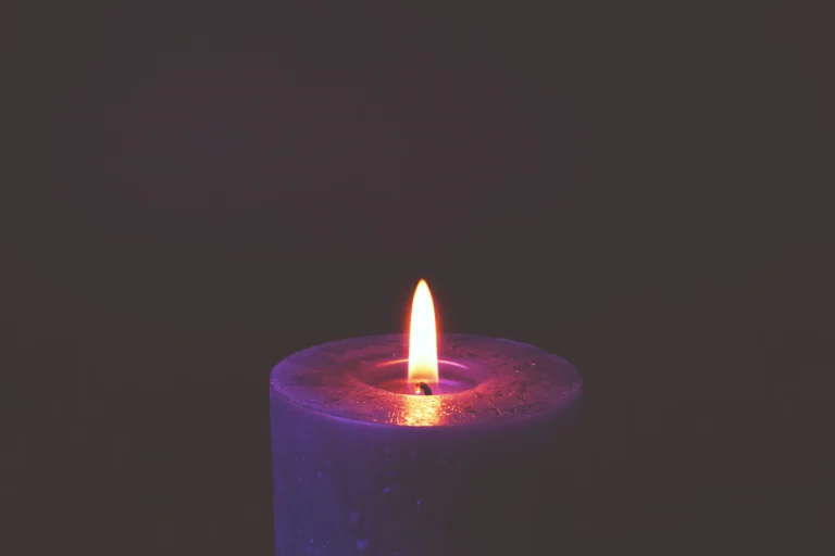 A single candle flame glowing in the darkness