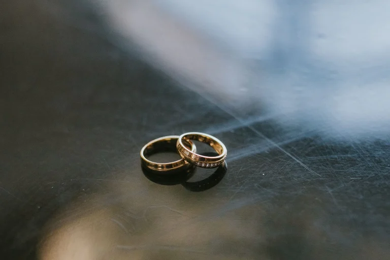 Two gold wedding rings on a reflective surface