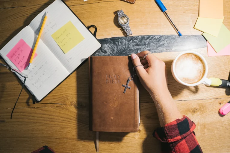 Bible study on a wooden desk with coffee, notes and an open Bible