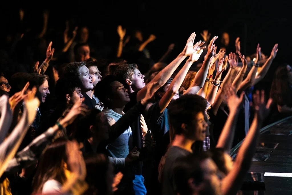 People raising their hands together in worship, open to the gifts of the Holy Spirit.