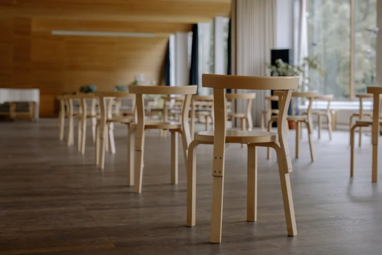 Empty wooden chairs in a quiet, light-filled room ready for a prayer session