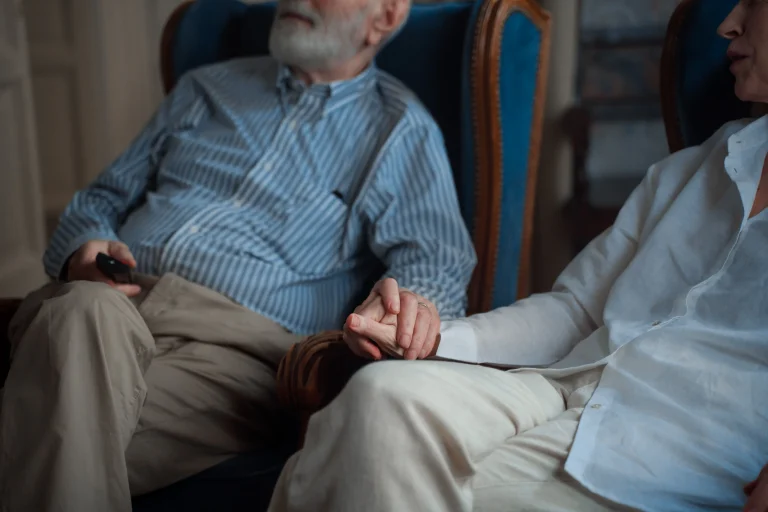 An elderly couple sitting together and holding hands