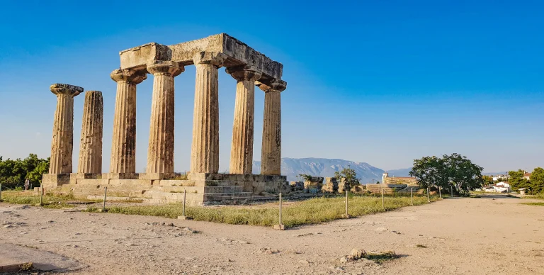 Ruins of the Temple of Apollo in ancient Corinth under a blue sky