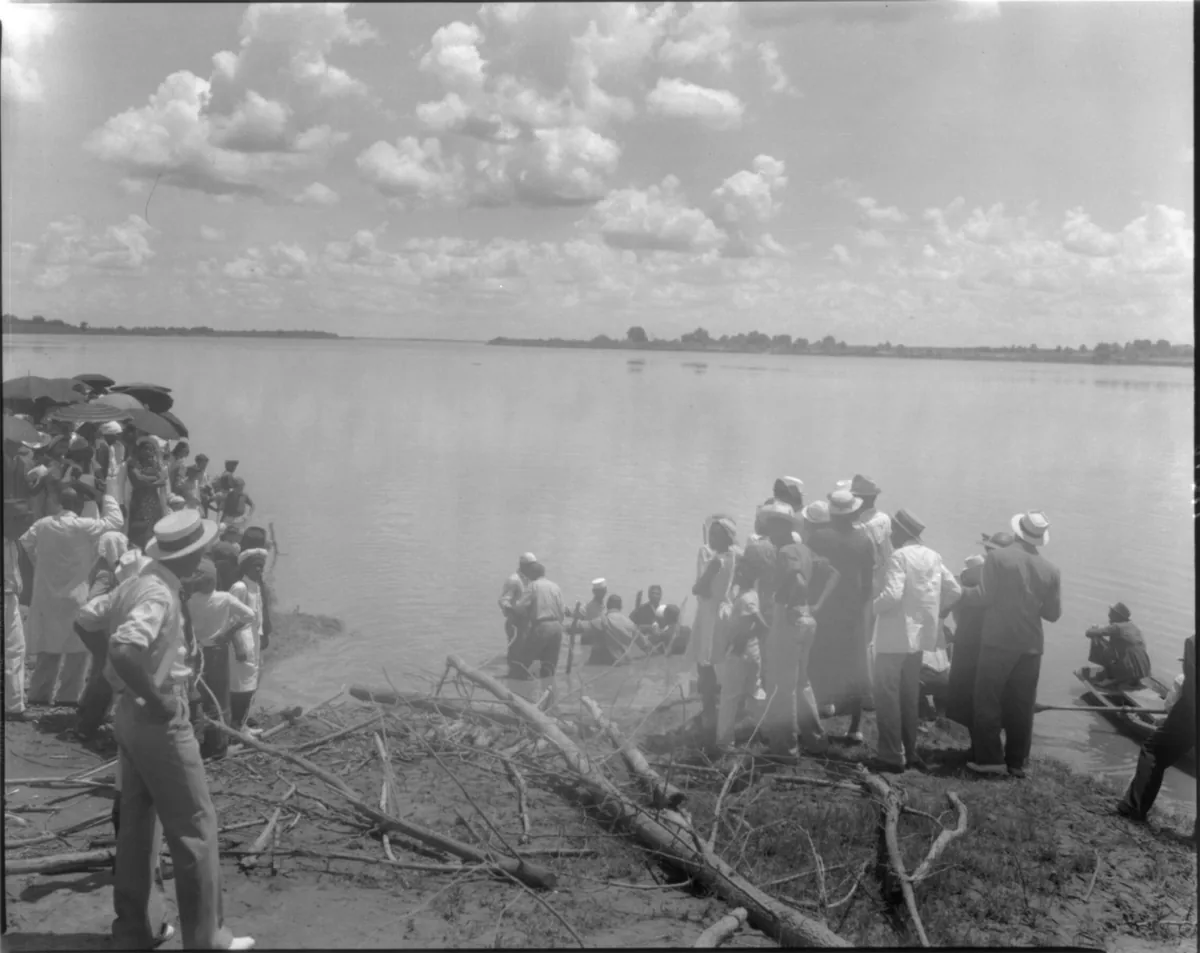 Black-and-white photo of a group standing shoulder-deep in the Mississippi River during a baptism by immersion in 1938