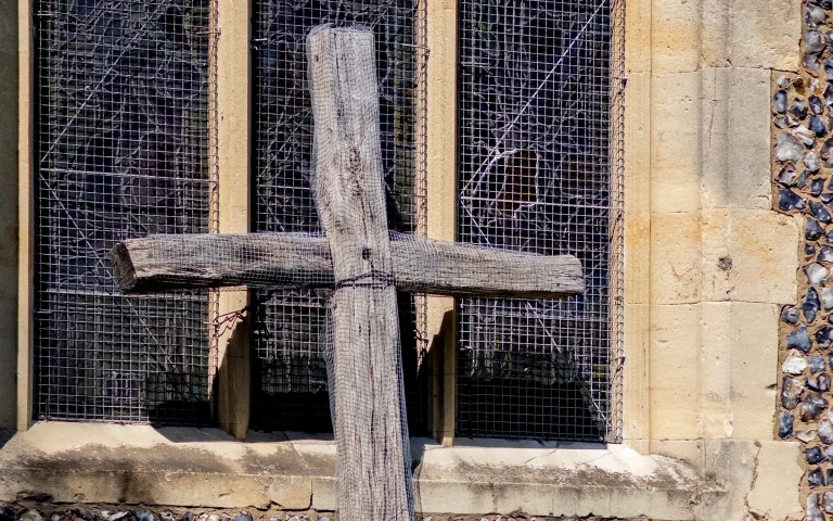 Wooden cross against the stone wall and windows of St Mary’s Church, Harrow on the Hill